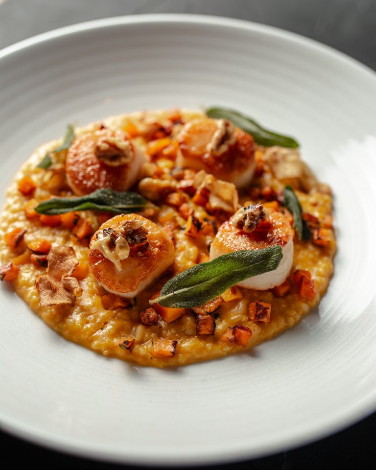 Seasonal seared scallop entree on a plate