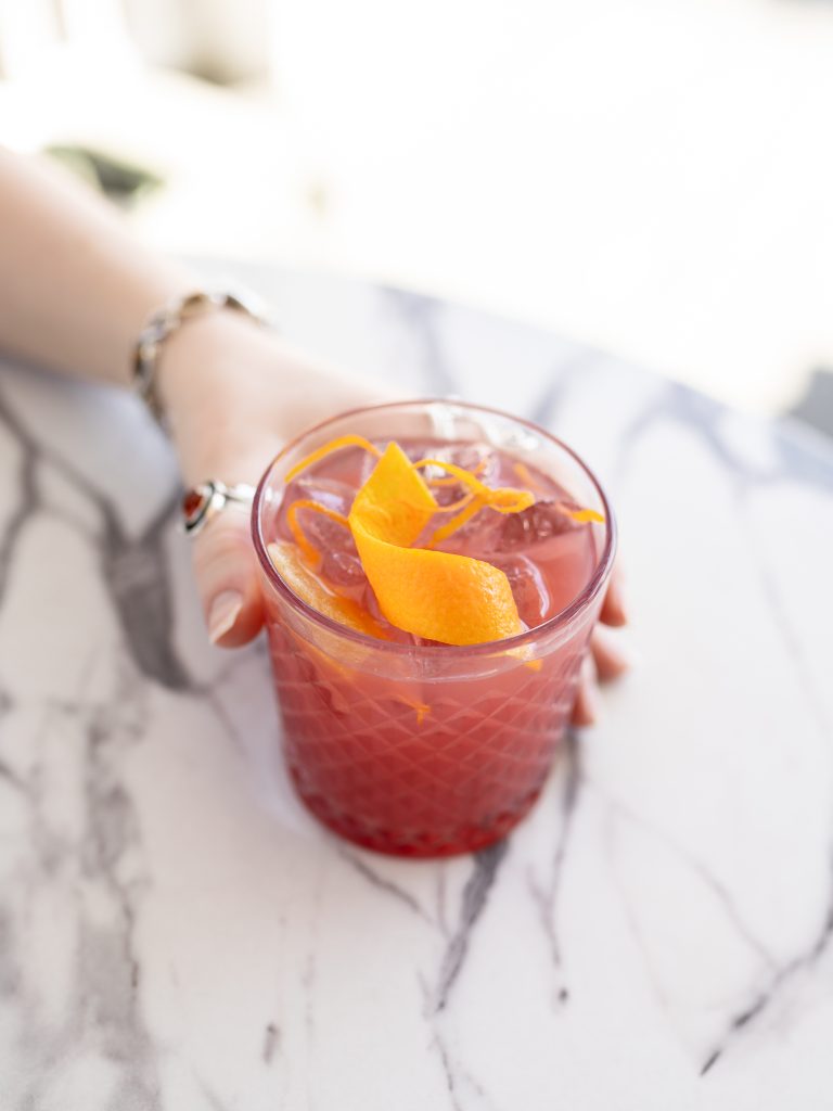 woman holding Pom Voyage cocktail in a glass