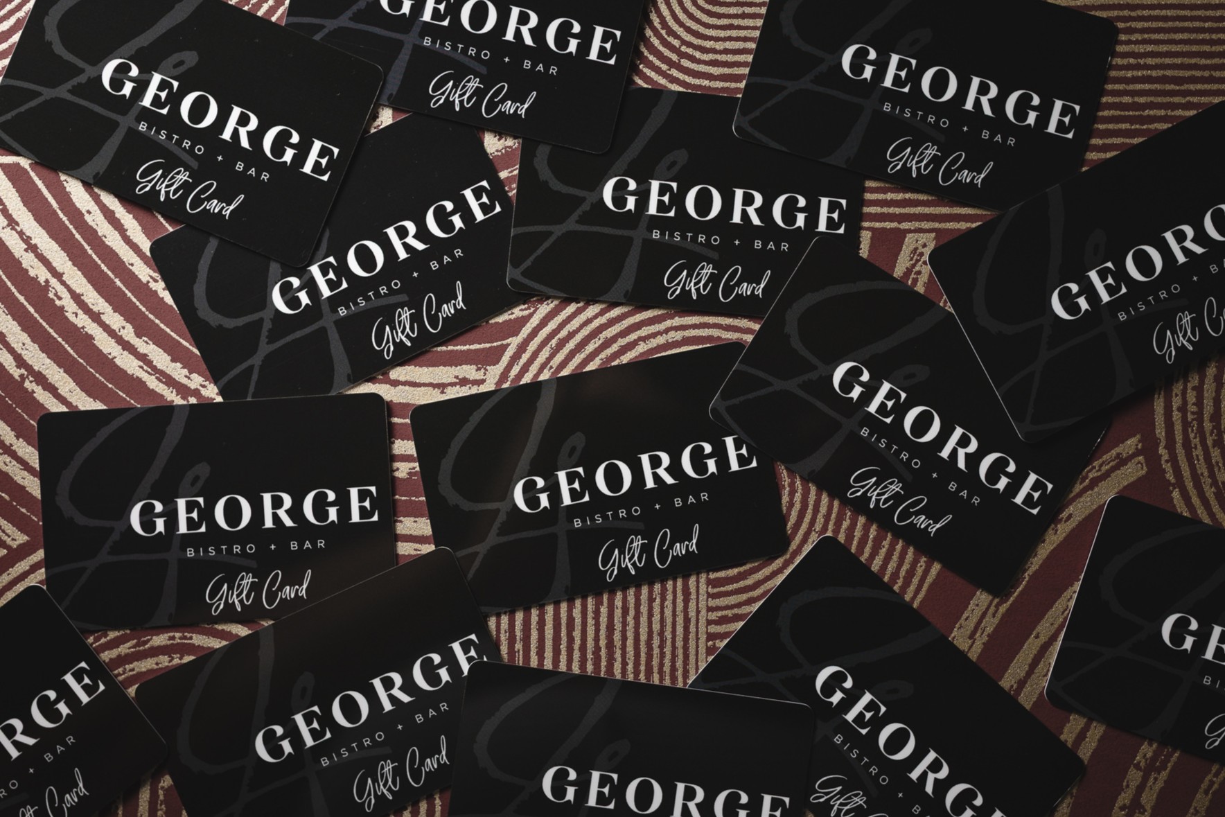 Multiple George Bistro + Bar Gift Cards spread out on a table