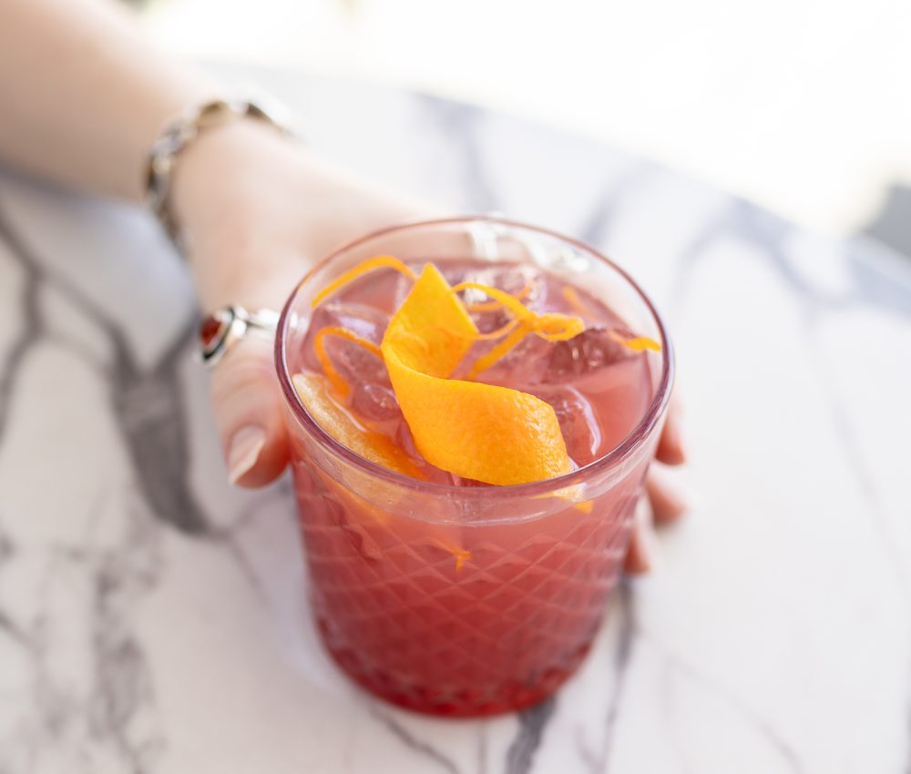 woman holding Pom Voyage cocktail in a glass