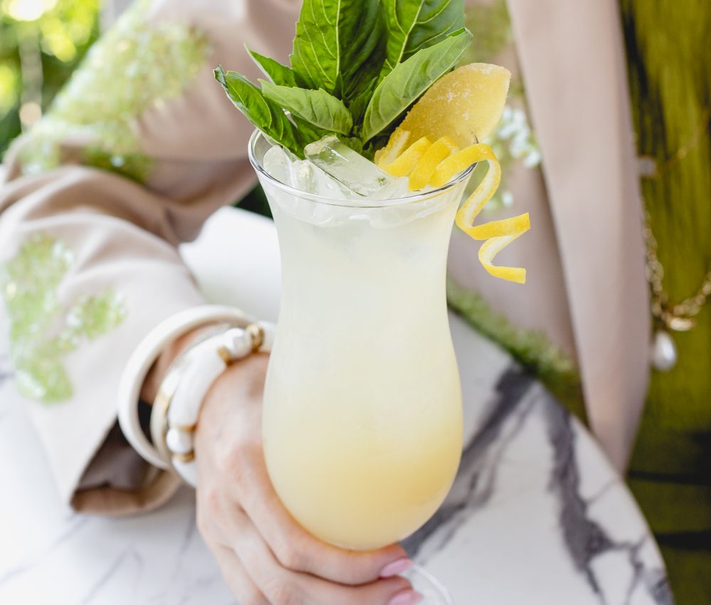 Woman sitting at a table holding a Bougie Water (a Non-Alcoholic drink) in a glass